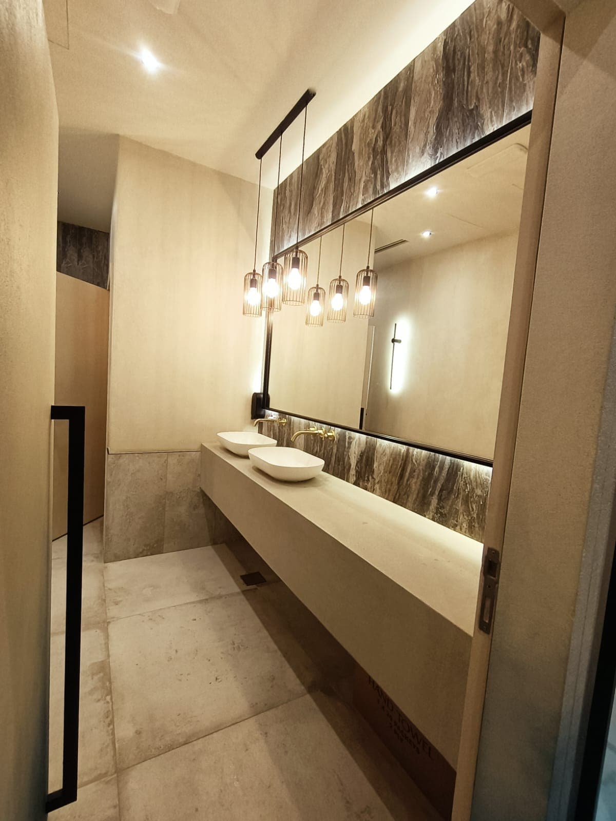 Double-vanity ensuite bathroom viewed from the entry, cage pendants lit