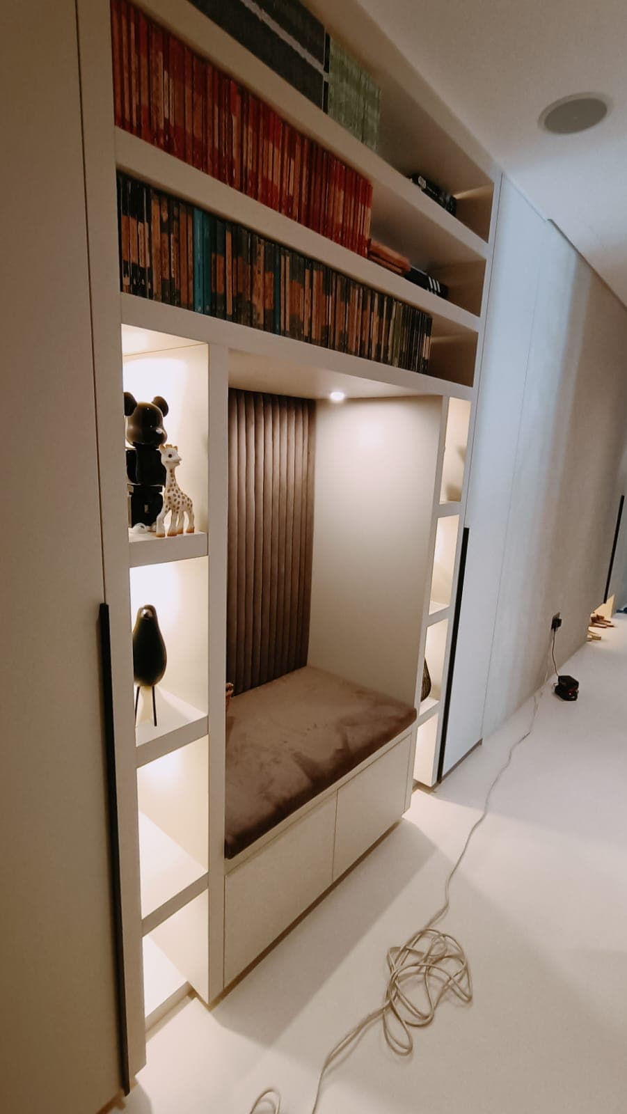 Built-in reading nook with cushioned bench and backlit shelving