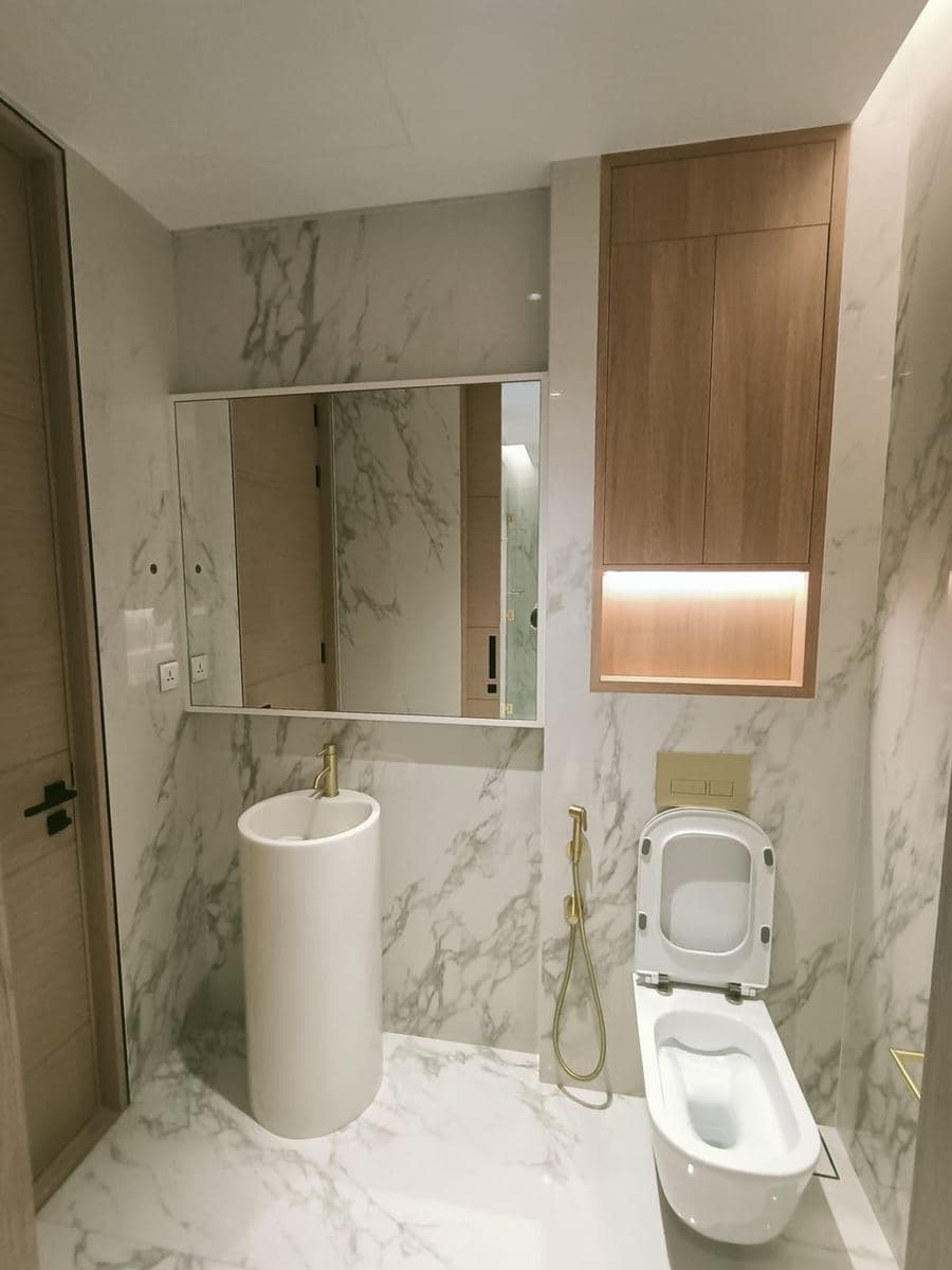 Marble bathroom with backlit mirror and wood cabinetry